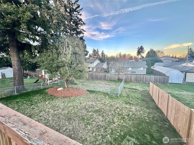 yard at dusk featuring a fenced backyard