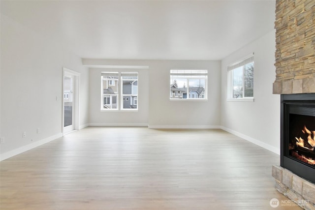 unfurnished living room with a fireplace, baseboards, and wood finished floors