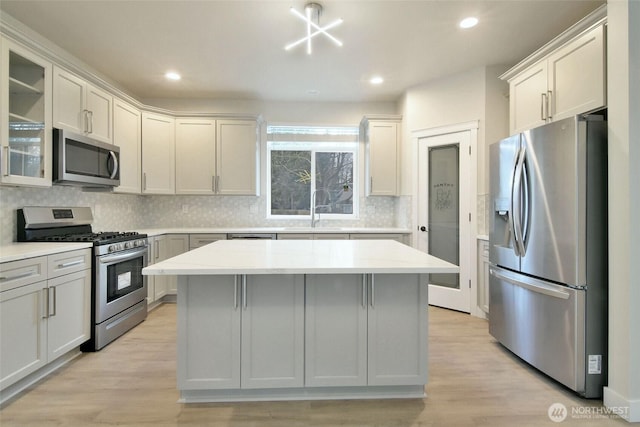 kitchen with stainless steel appliances, light wood-type flooring, a sink, and light countertops