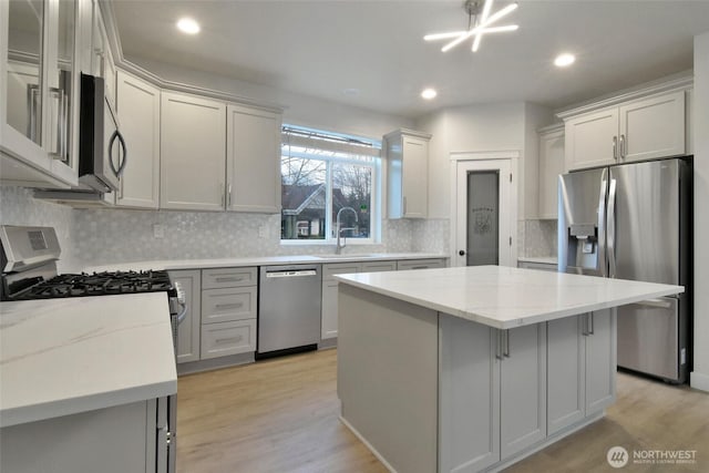 kitchen featuring light wood-type flooring, appliances with stainless steel finishes, a sink, and a center island