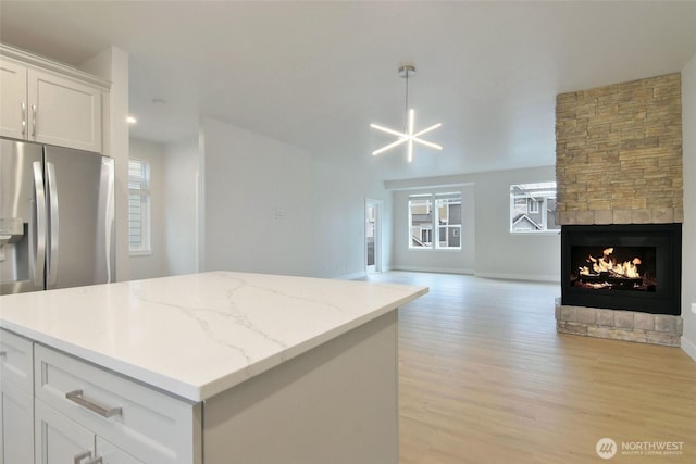 kitchen featuring a fireplace, a kitchen island, white cabinets, open floor plan, and light wood-type flooring