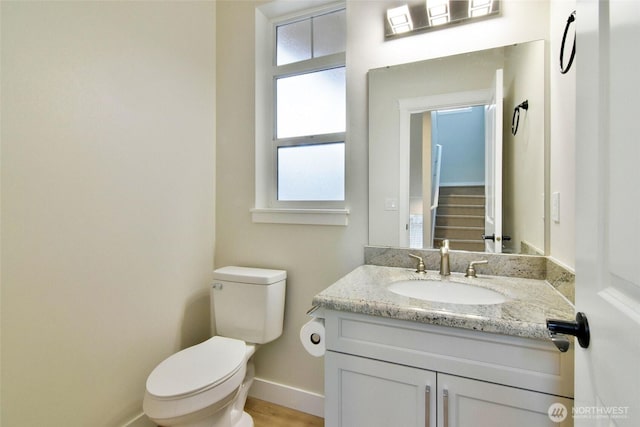 half bath featuring vanity, toilet, and baseboards