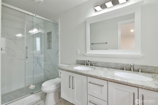 bathroom featuring marble finish floor, a marble finish shower, a sink, and toilet