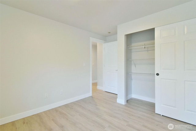 unfurnished bedroom featuring light wood-type flooring, a closet, and baseboards