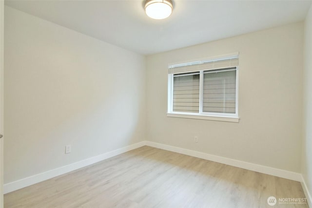 spare room with baseboards and wood finished floors