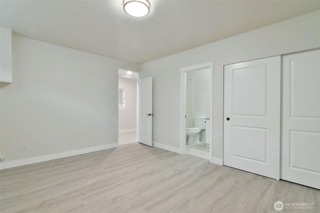 unfurnished bedroom with a closet, connected bathroom, baseboards, and wood finished floors