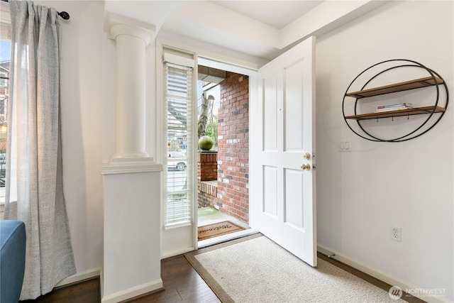 entryway featuring baseboards, ornate columns, and wood finished floors