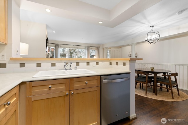 kitchen with dark wood finished floors, dishwasher, wainscoting, light countertops, and a sink