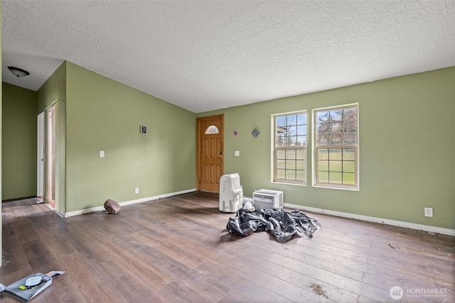 unfurnished room with lofted ceiling, a textured ceiling, wood finished floors, and baseboards