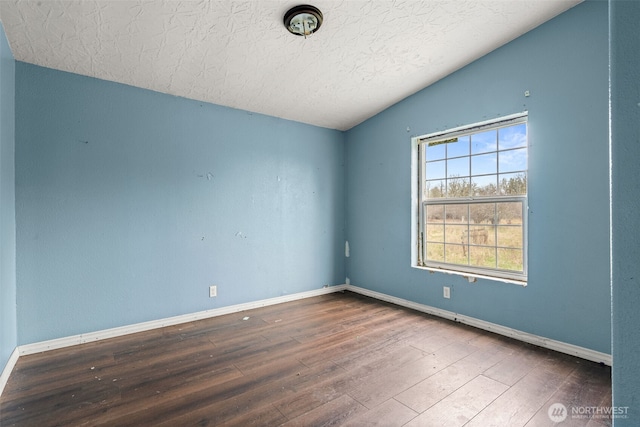 empty room featuring lofted ceiling, a textured ceiling, baseboards, and wood finished floors