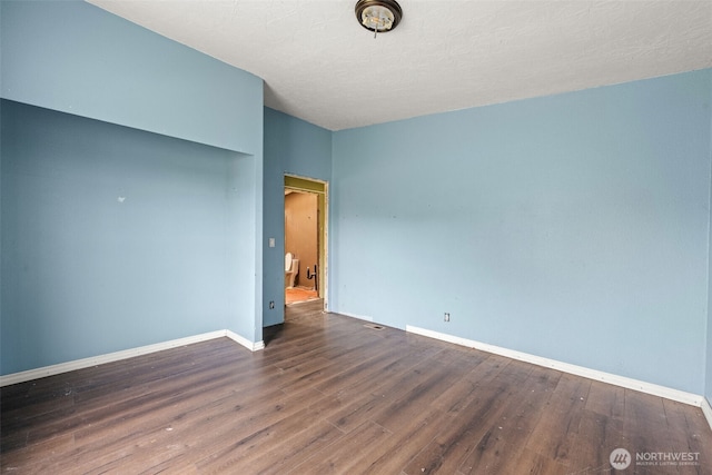 empty room featuring a textured ceiling, baseboards, and wood finished floors