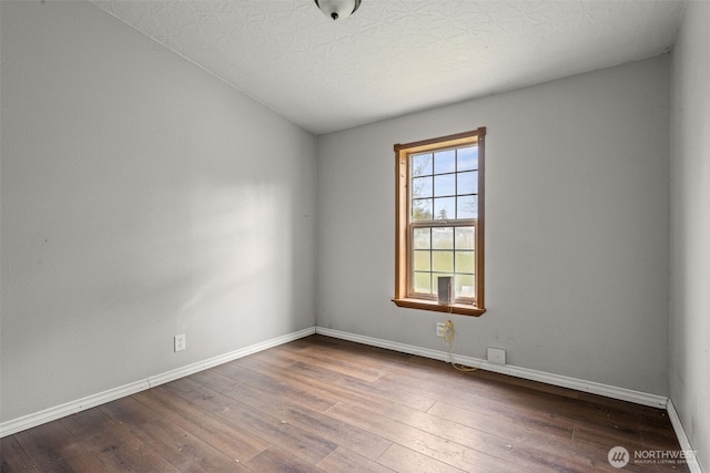 spare room with dark wood-style floors, baseboards, and a textured ceiling