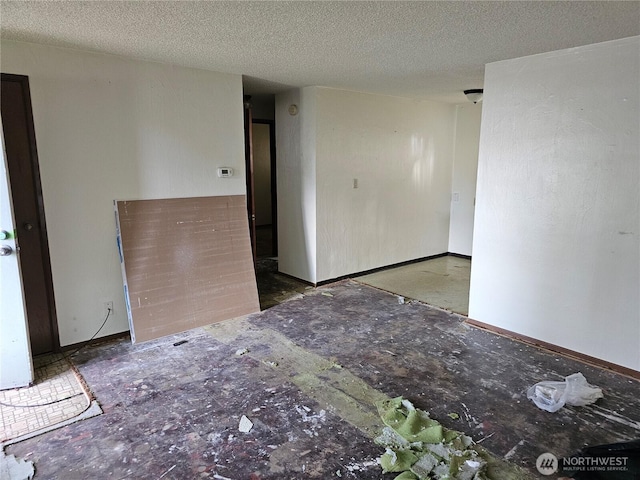 unfurnished room with a textured ceiling and baseboards