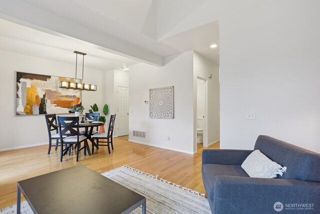 living area with baseboards, visible vents, light wood-style floors, beam ceiling, and recessed lighting