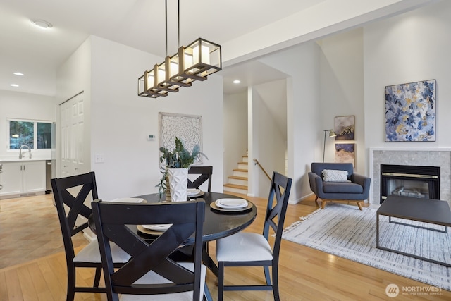 dining room featuring stairs, recessed lighting, a tiled fireplace, and light wood-style floors