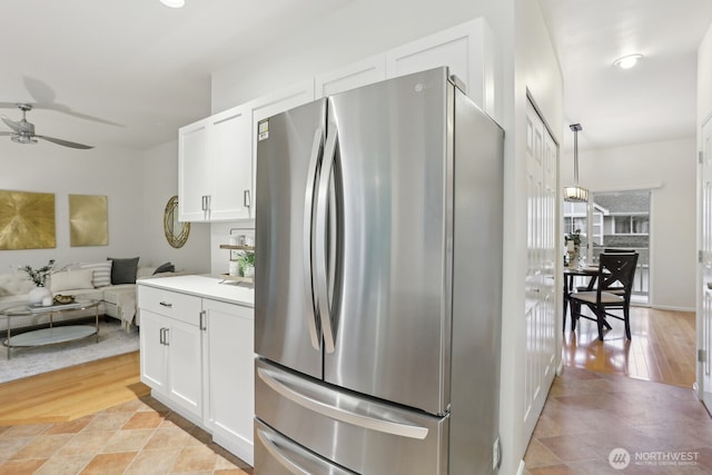 kitchen with a ceiling fan, open floor plan, freestanding refrigerator, light wood-type flooring, and white cabinetry