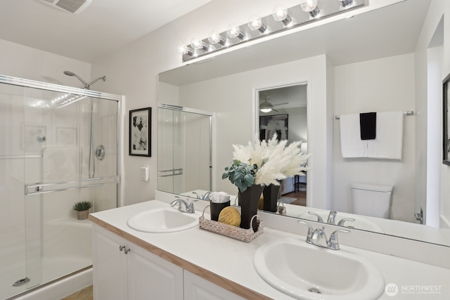 bathroom featuring double vanity, a stall shower, a sink, and visible vents