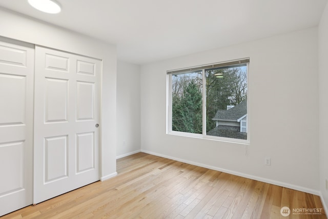 unfurnished bedroom featuring a closet, baseboards, and wood finished floors