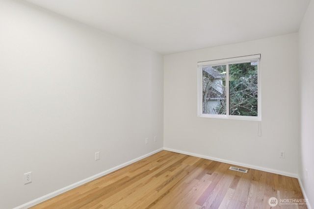 unfurnished room with baseboards, visible vents, and wood finished floors