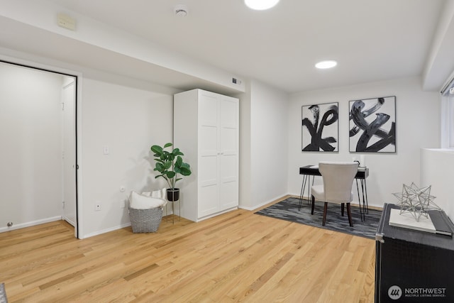 office space with light wood-style floors, visible vents, and baseboards