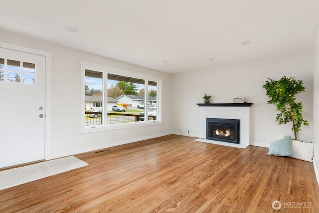 unfurnished living room featuring light wood finished floors, baseboards, a fireplace, and visible vents