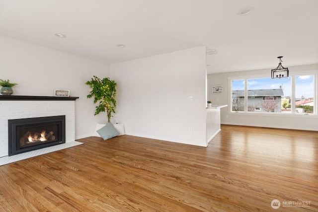 unfurnished living room with a fireplace, baseboards, and wood finished floors