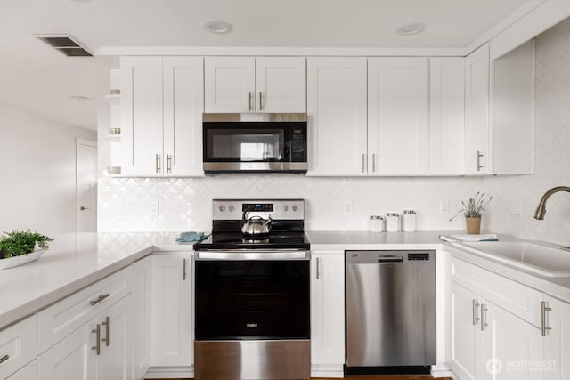 kitchen featuring a sink, visible vents, white cabinets, light countertops, and appliances with stainless steel finishes