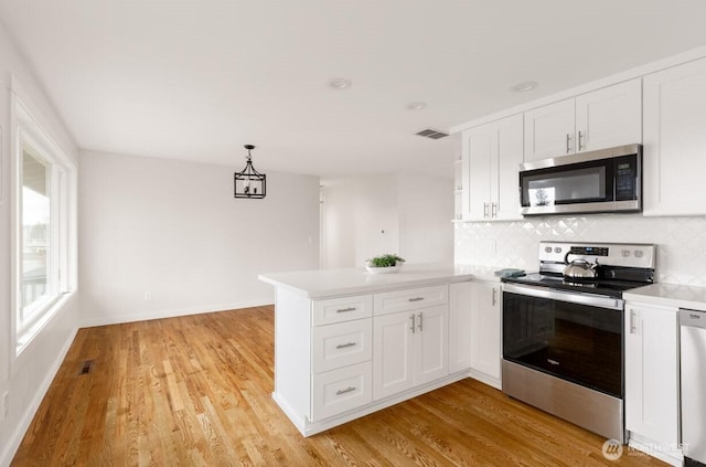 kitchen with visible vents, white cabinets, a peninsula, stainless steel appliances, and light wood-type flooring