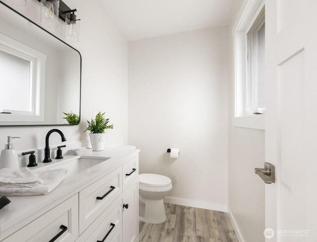 bathroom with vanity, wood finished floors, toilet, and baseboards