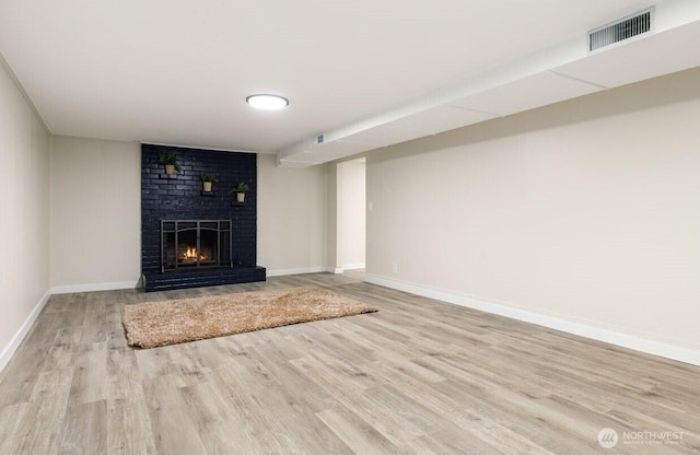 unfurnished living room featuring baseboards, a fireplace, visible vents, and wood finished floors