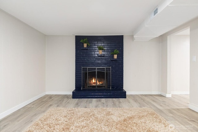 interior details with a fireplace, wood finished floors, visible vents, and baseboards