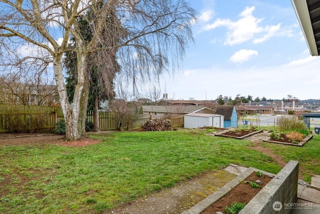 view of yard featuring a garden, a fenced backyard, a shed, and an outdoor structure