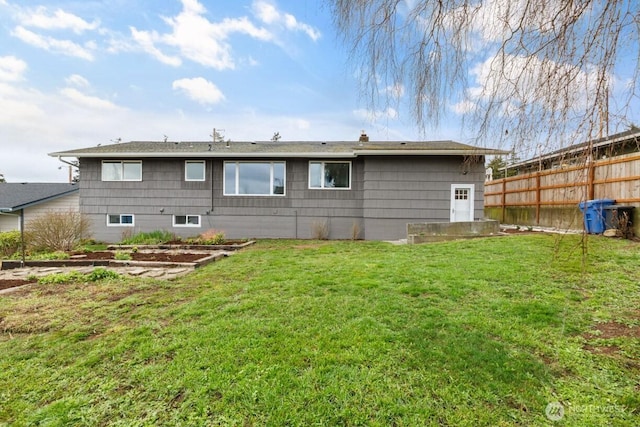 rear view of house with a lawn and fence