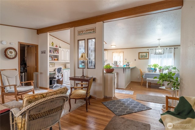 sitting room featuring a textured ceiling, baseboards, wood finished floors, and an inviting chandelier