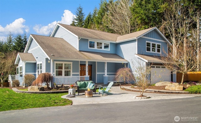 traditional-style home featuring an attached garage, driveway, a porch, and roof with shingles