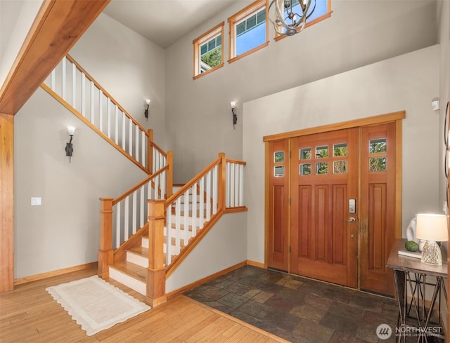 entryway with a towering ceiling, stairway, baseboards, and wood finished floors