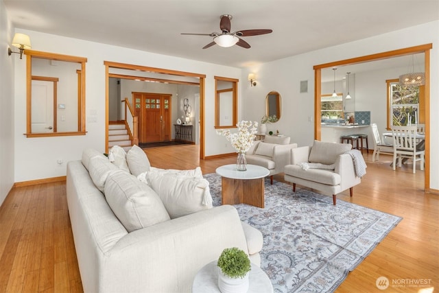 living room featuring stairs, wood finished floors, a ceiling fan, and baseboards