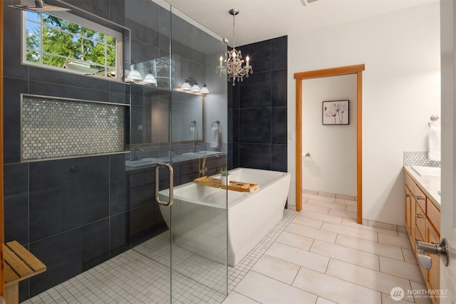 bathroom with a notable chandelier, a freestanding bath, vanity, a shower stall, and tile patterned flooring