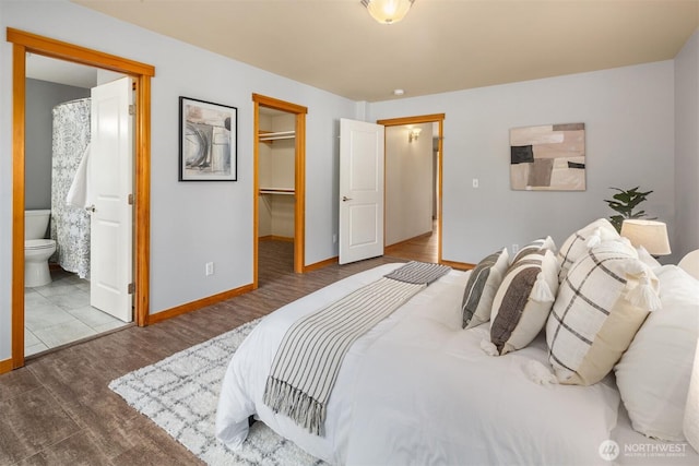 bedroom featuring baseboards, connected bathroom, wood finished floors, a spacious closet, and a closet