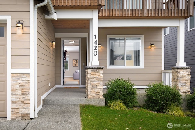 property entrance with a garage, stone siding, and a balcony