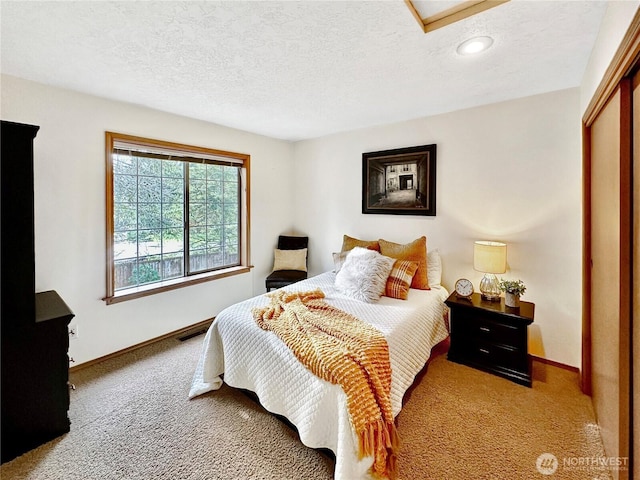 carpeted bedroom featuring visible vents, a textured ceiling, and baseboards