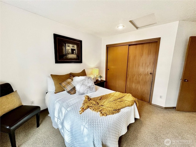 carpeted bedroom with a closet, attic access, and baseboards