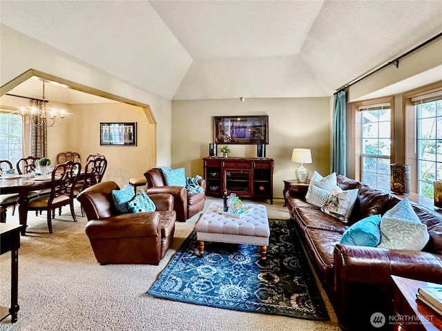 carpeted living area featuring vaulted ceiling and an inviting chandelier