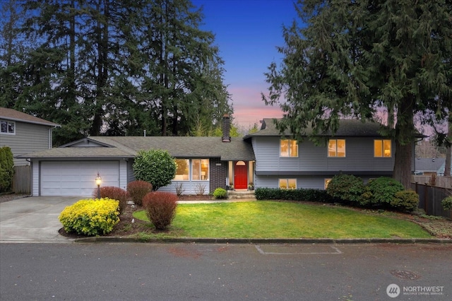 tri-level home with driveway, a garage, a chimney, fence, and a front lawn