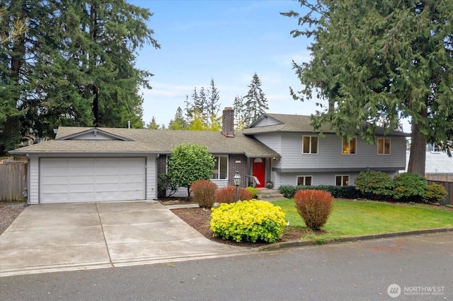 split level home featuring a garage, concrete driveway, a chimney, fence, and a front lawn