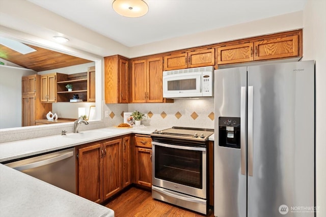 kitchen featuring stainless steel appliances, brown cabinetry, a sink, and light countertops