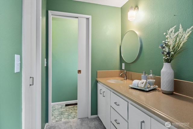 bathroom featuring visible vents, baseboards, and vanity