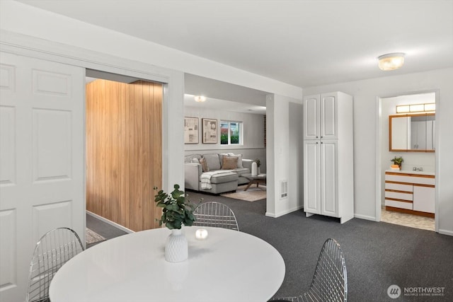 dining space with dark colored carpet and baseboards