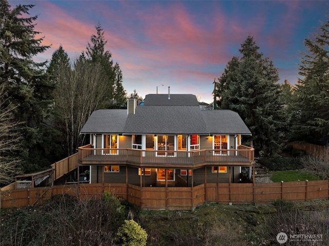 back of property with a wooden deck, fence private yard, and a chimney