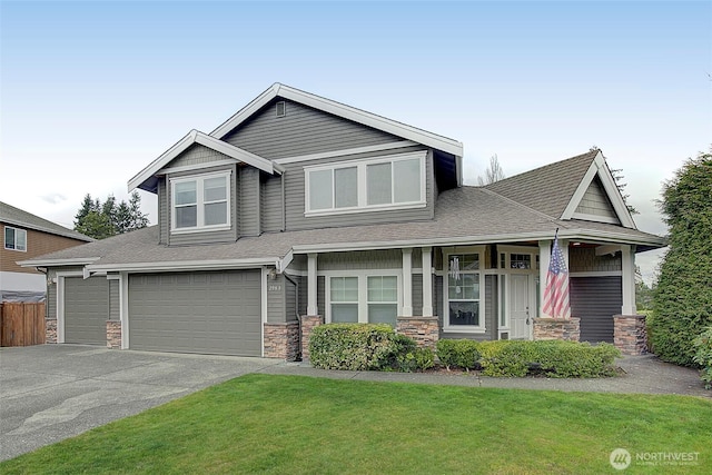 view of front facade with driveway, stone siding, a front yard, a shingled roof, and a garage